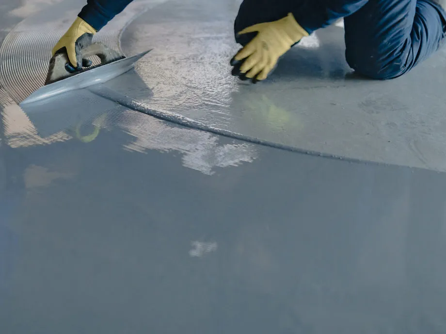 An individual applying grey color epoxy flooring